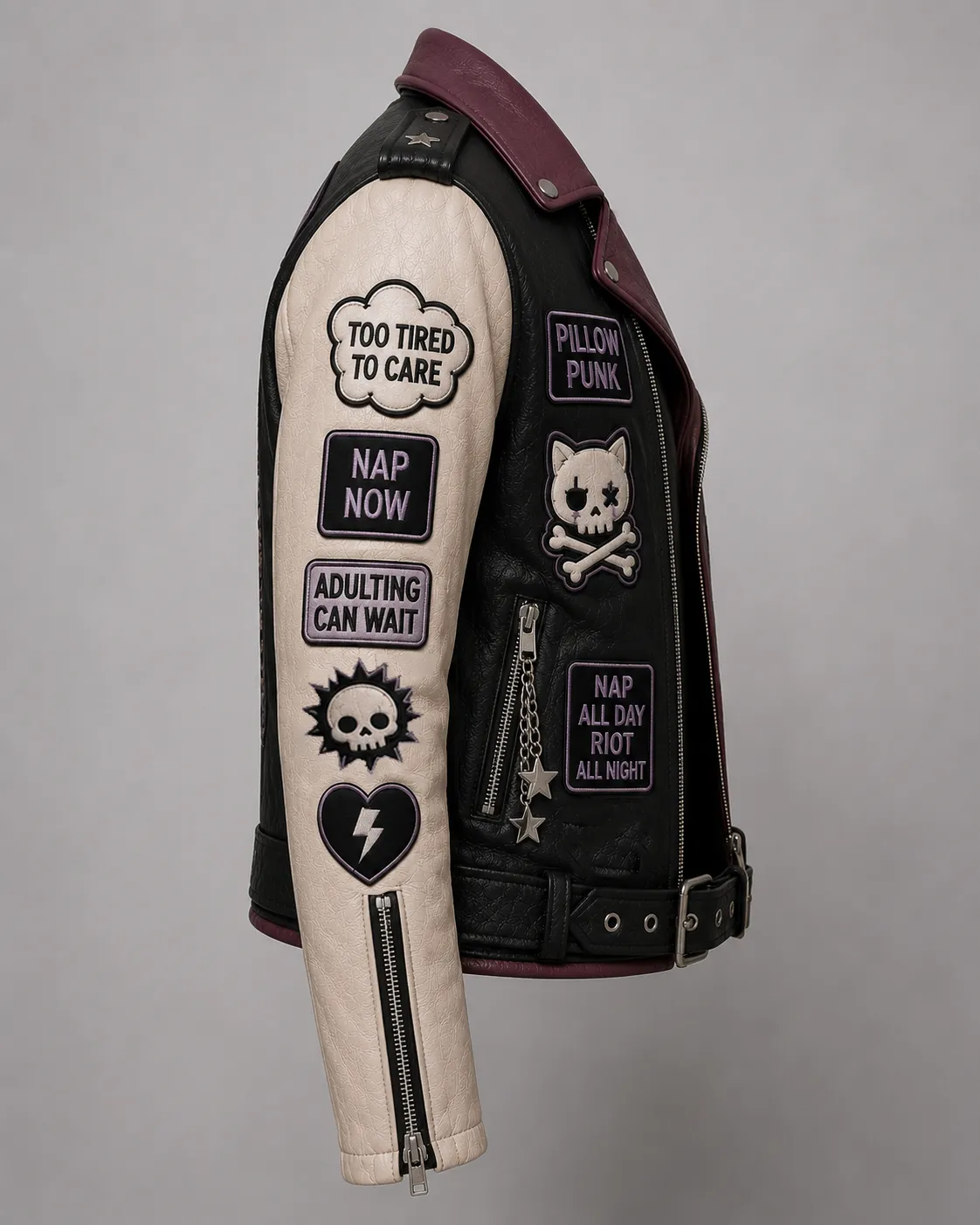 Right side view showing off-white leather sleeve with TOO TIRED TO CARE, NAP NOW, ADULTING CAN WAIT patches, skull motif, and heart lightning bolt emblem.